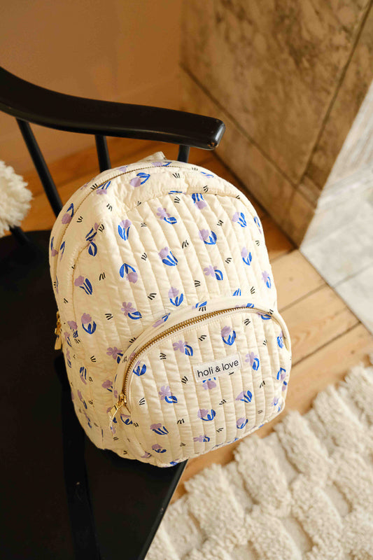 Sac à dos imprimé petites fleurs lilas, en coton matelassé. Accessoire enfant ou adulte idéal pour ranger toutes ses affaires d'école et de voyage.