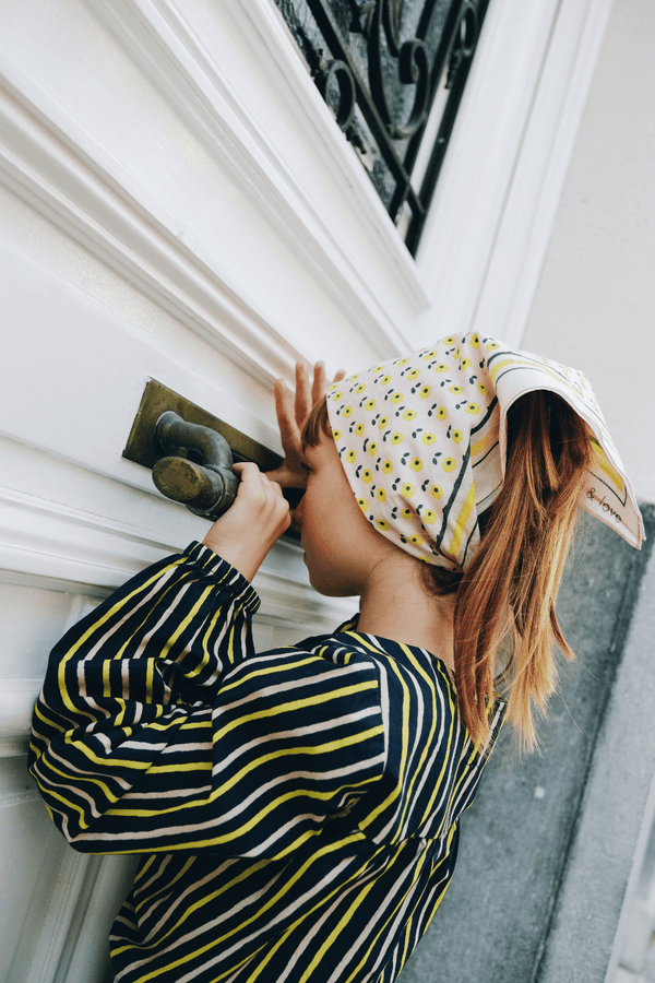 Fille portant le foulard BRIGITTE imprimé petites fleurs jaunes et la chemise à manches longues SASHA motif à rayures bleu marine rose et jaune, vêtement en coton bio style vintage